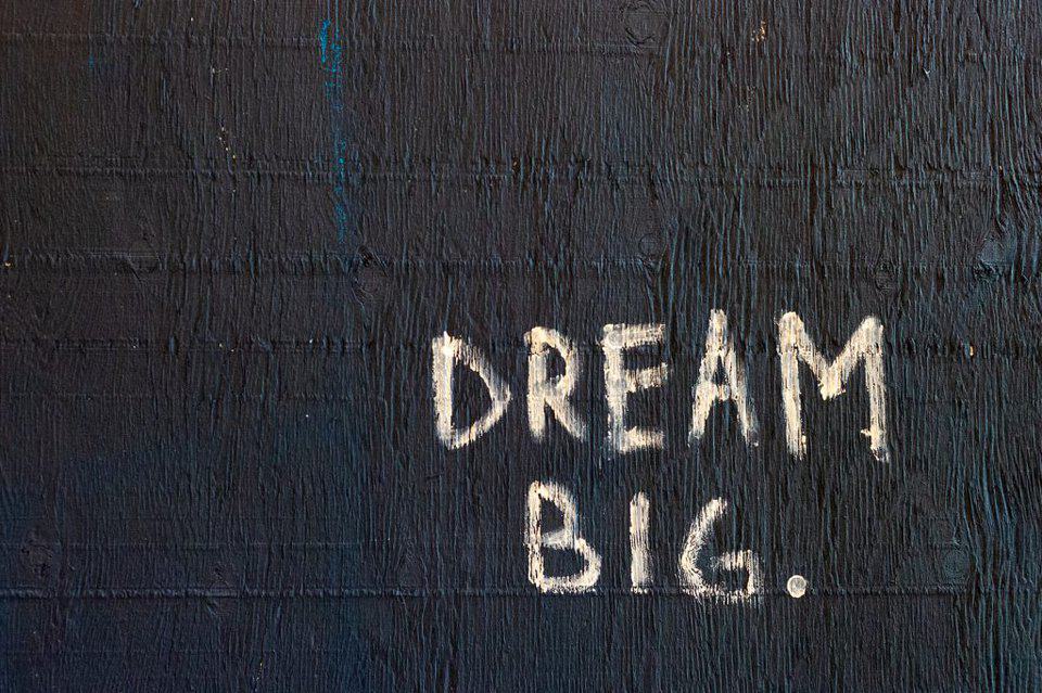 Wat is het verschil tussen manager en management? Foto van een muur met de woorden "dream big"